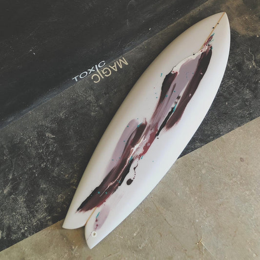 White surfboard with abstract design on a black surface