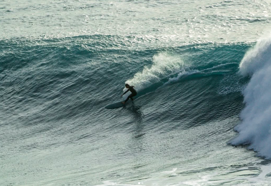 Matthew doing a carve on a big wave whilst ridinga diamond tail single fin.