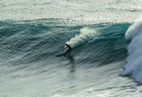 Matthew doing a carve on a big wave whilst ridinga diamond tail single fin.