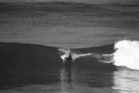 Black and white picture of Matthew doing a layback manoeuvre on a step up model surfboard.